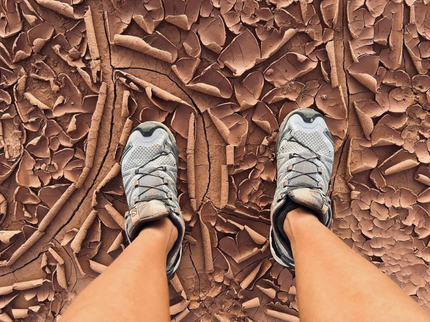 Missy in running shoes, standing on dried rez mud.